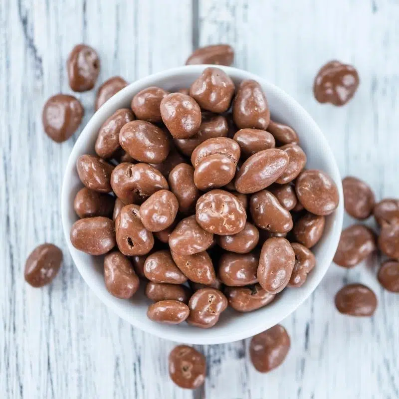 A white bowl filled with chocolate raisins.