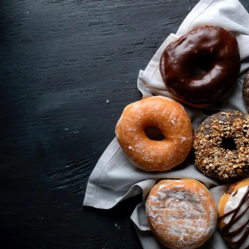 An image of a black surface with a plate to one side with mixed donuts.