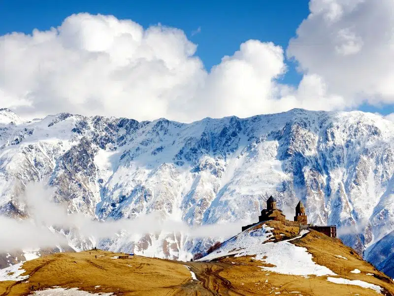 View of a Georgian monsatery against snowcapped mountains