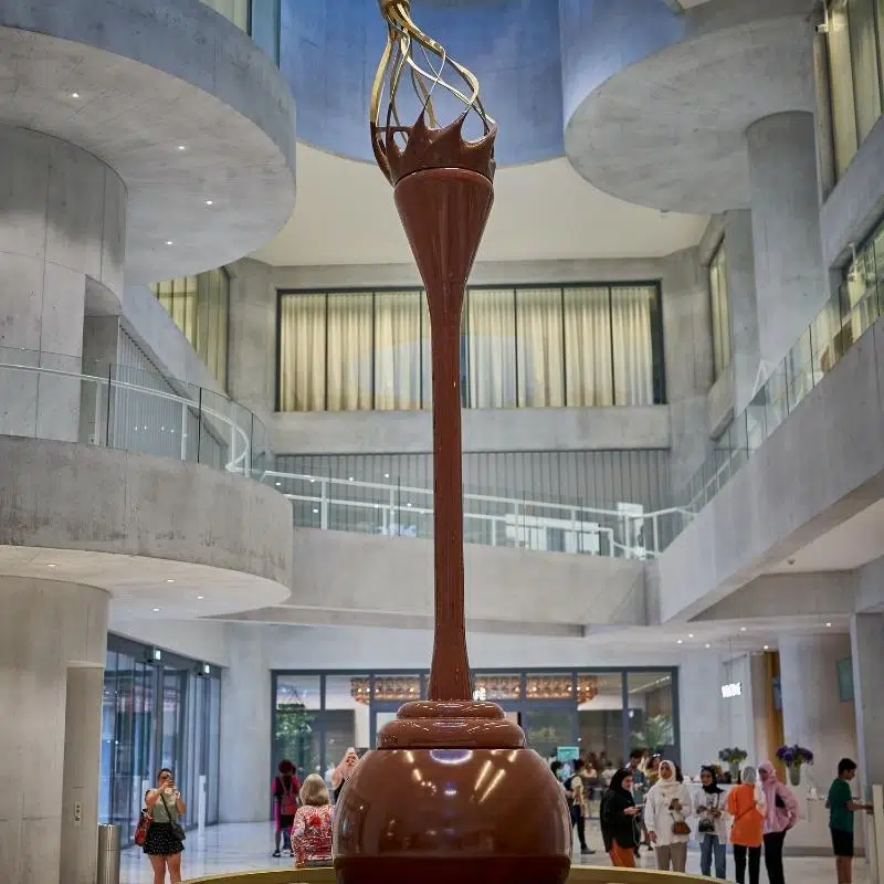 An image of a giant chocolate fountain with a whisk on top