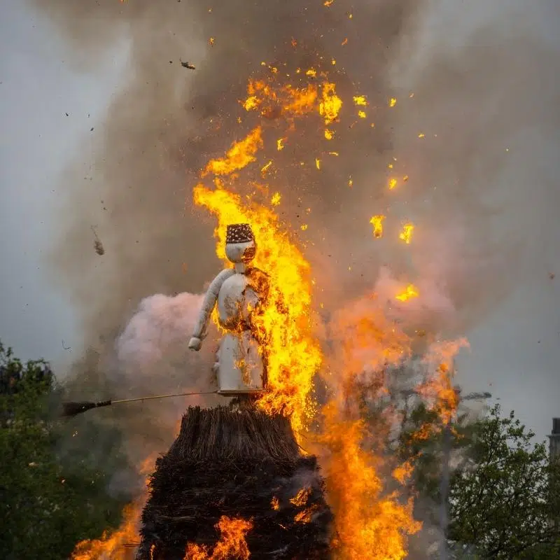 An Image of a fake snowman set on top of a pyre which is on fire.