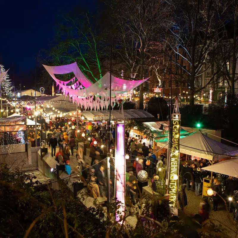A nightie image of the district of Schwabing, with street stalls and multi coloured fairy lights