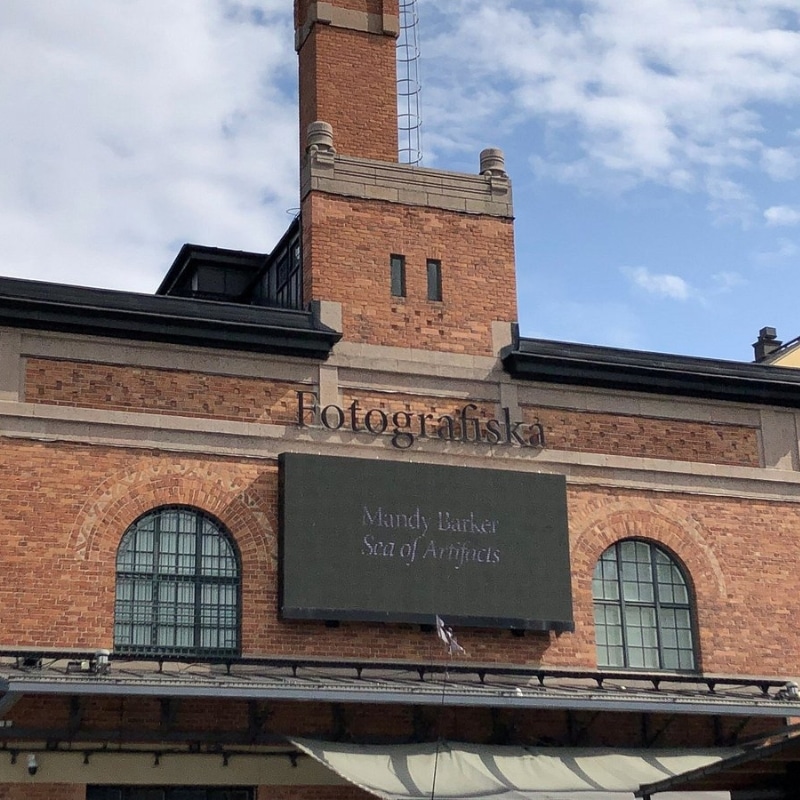 A close up image of the entrance to the FOTOGRAFISKA museum, with the sign on a brick facade, with a small tower.