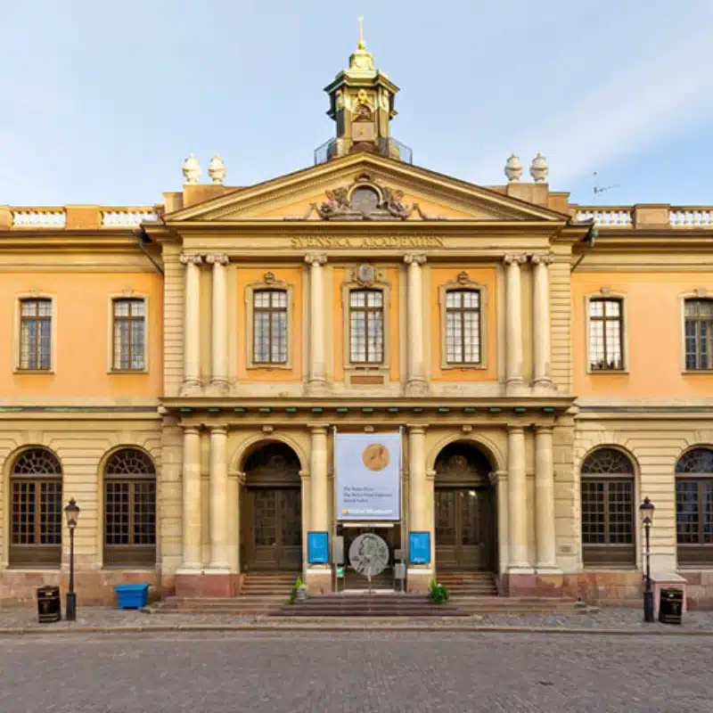 An image of the yellow and cream building with faux columns and arched entries.