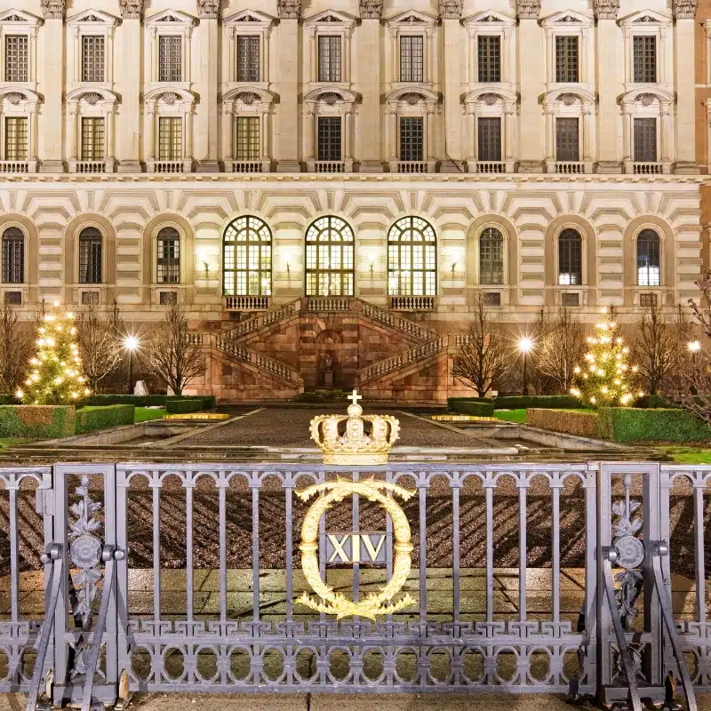 This image shows the front of the very large royal palace in Stockholm, 3 arched windows at the bottom are lit.