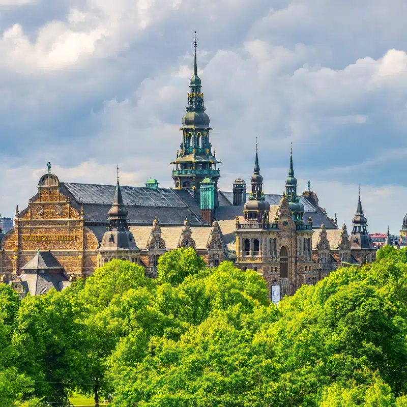 An image of the Nordiska Museet, the building is in the renaissance style, with many green copper spires and decorated with gold