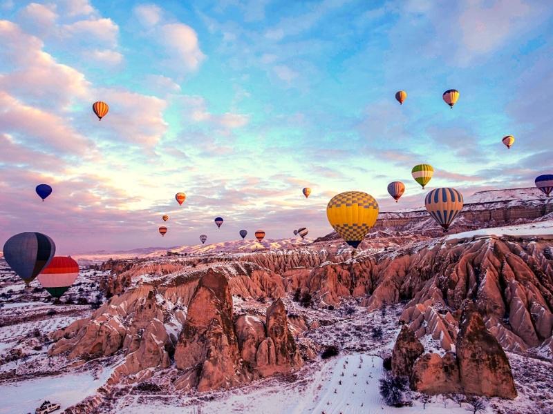 Cappadocia in the snow with hot air balloons flying above