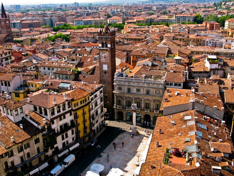 terracotta roofs on medieval buildings around a square, with a red brick square tower in the corner of the square