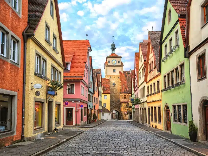 colorful houses lining a cobbled road with a medieval church between the houses