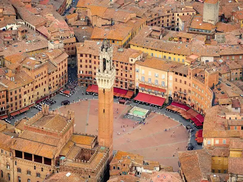 clay brick buildings around a round central square, with a tall tower in the forground