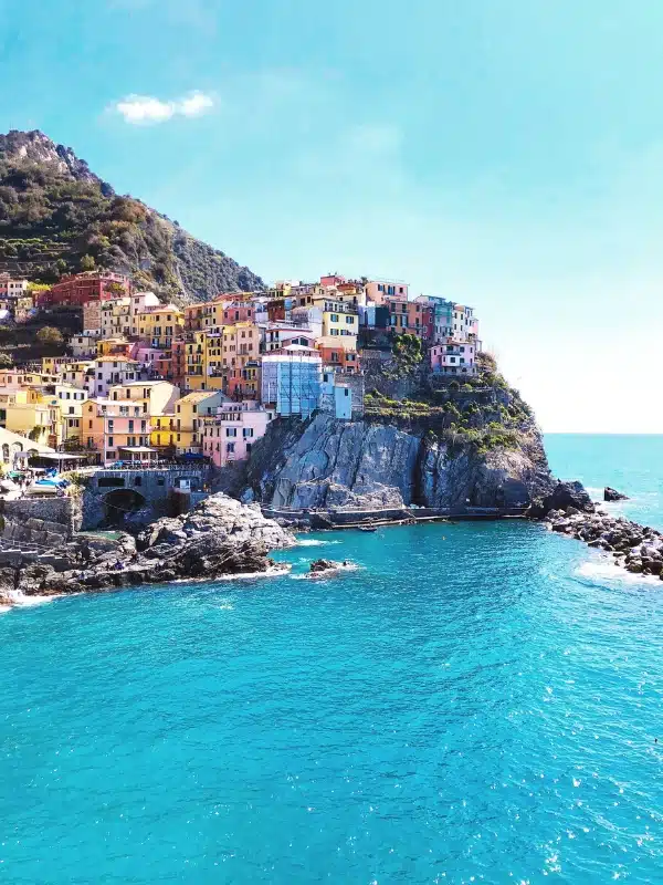 Colored houses atop a rock next to a turquoise blue sea