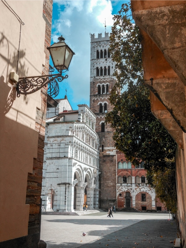 a view from an alley of a tall square church tower