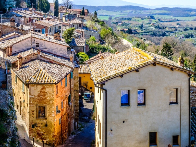 terracotta tiled roofs on traditional Italian vilage houses with a view of Tuscany beyond