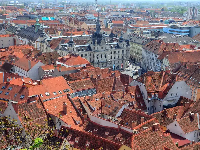 View across terracotta tiled rooftops to a Baroque building with a spire