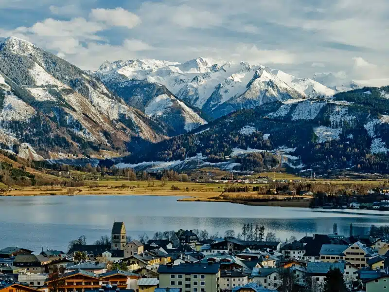 View across a town over a lake to large snow covered mountains