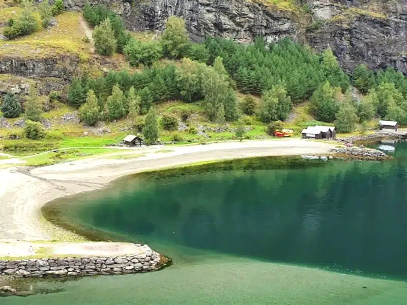 fjord beach with green water and small wooden huts