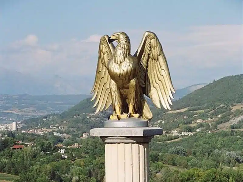 Golden eagle statue on a colum on the Route Napoleon above the landscape of Provence