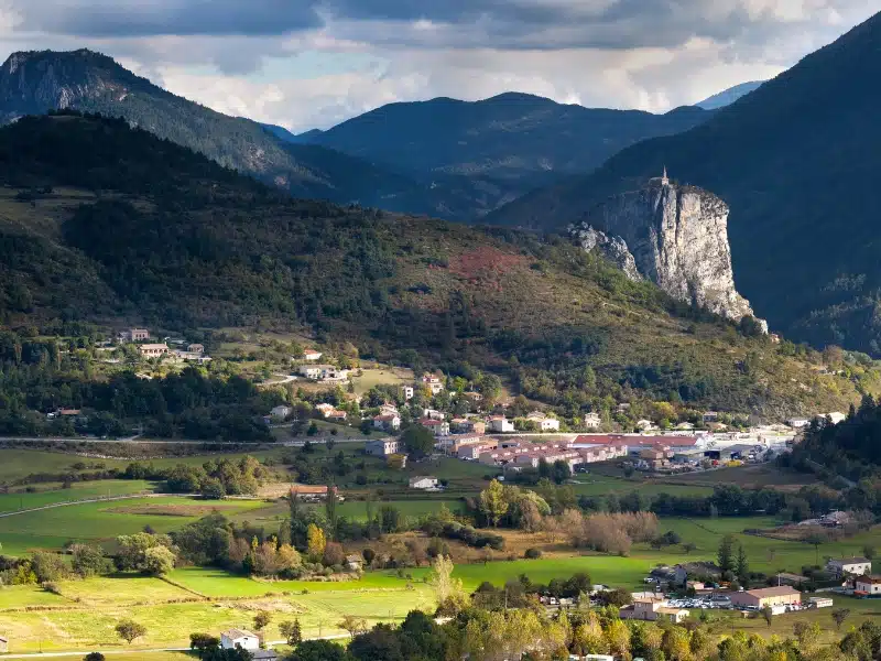 Landscape in south eastern France with a large rock in the distance, and a small church on top of the rock