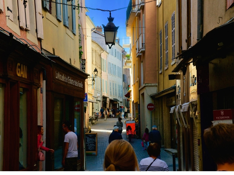 A cobbled alley in France lined with colourful houses with shutters