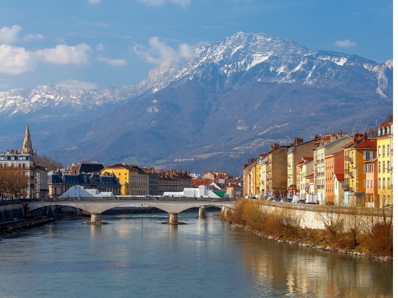 A riverside city with a modern bridge and historic houses