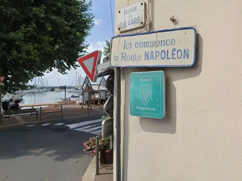 Road signs for the route Napoloen on a wall by the sea