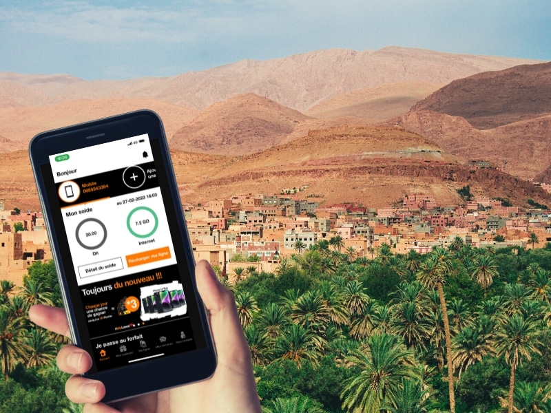 mobile phone with Orange Morocco app open in front of desert and palm trees