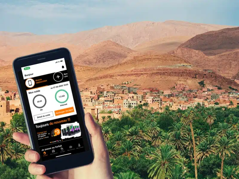 mobile phone with Orange Morocco app open in front of desert and palm trees
