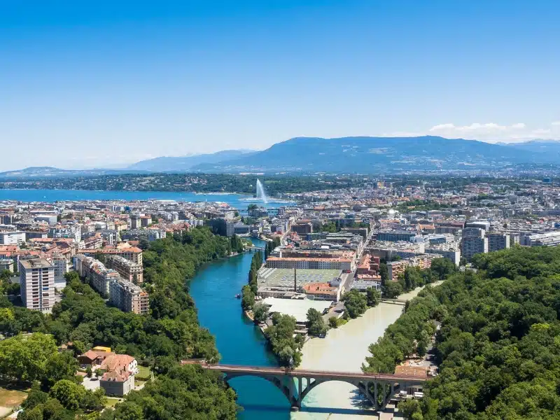 Aerial view of a leafy city with a cream river metting a blue river