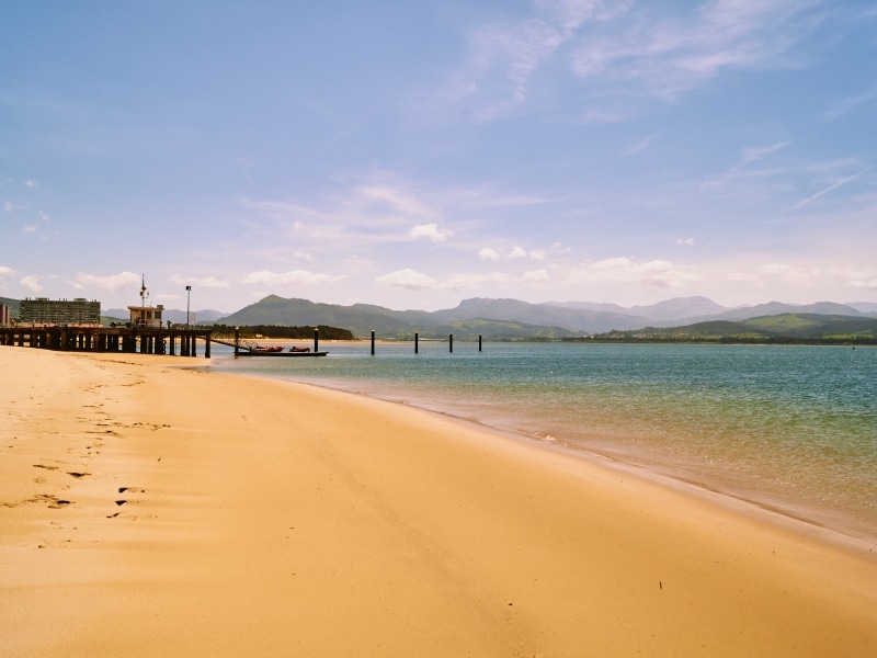 A long sandy beach with a small pier