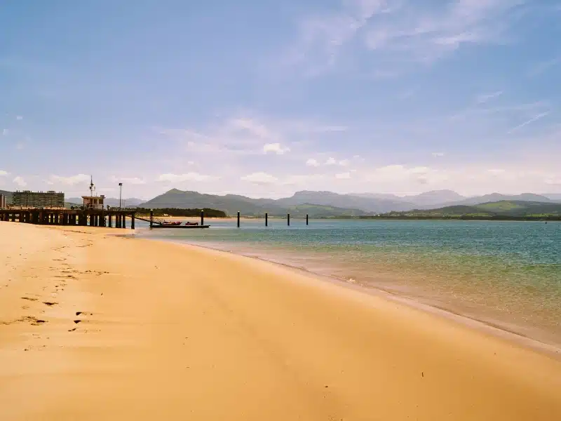 A long sandy beach with a small pier
