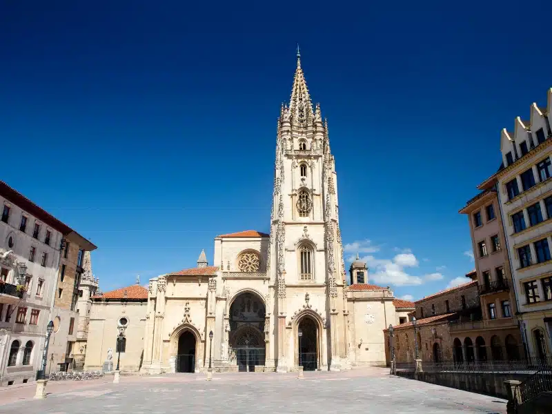 A creamy stone church with intricate carvings and wrought iron gates