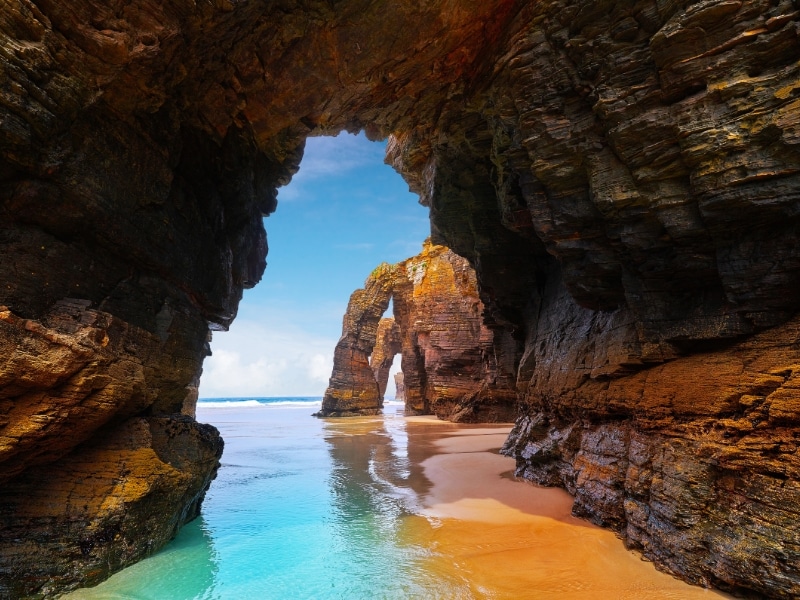 rock arches above golden sands and turquoise waters
