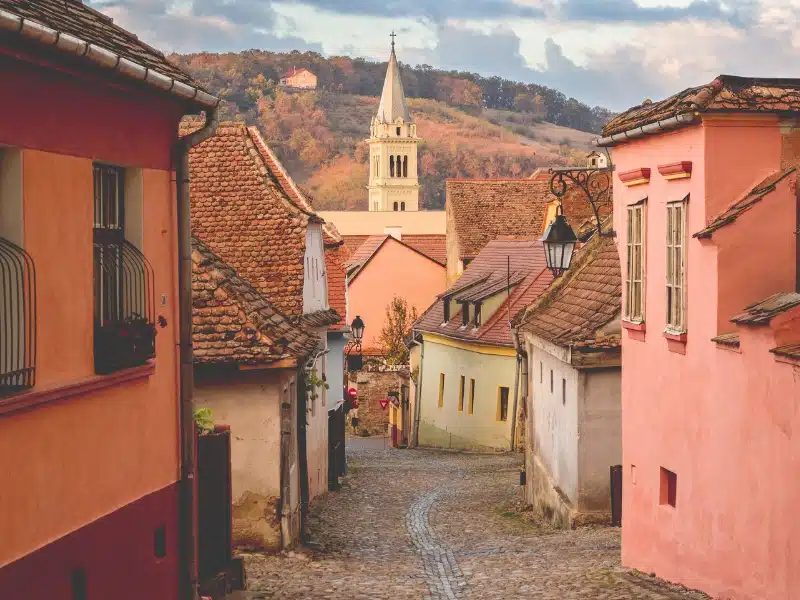 pink wahes houses lined a wonky cobbled street with a church in the distance