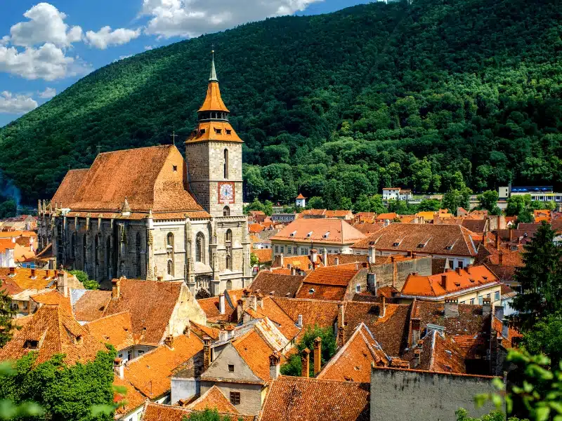 red roofed church above red roofed buildings surrounded by green trees 