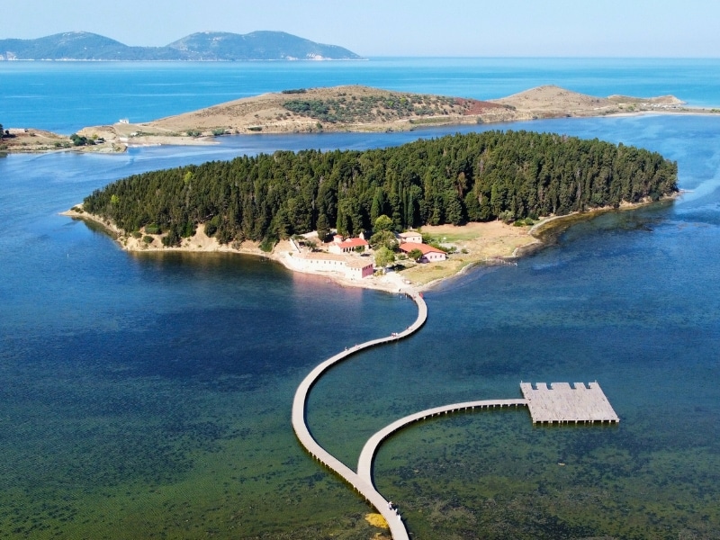 small island with wooden boardwalk from the mainland over green and blue sea
