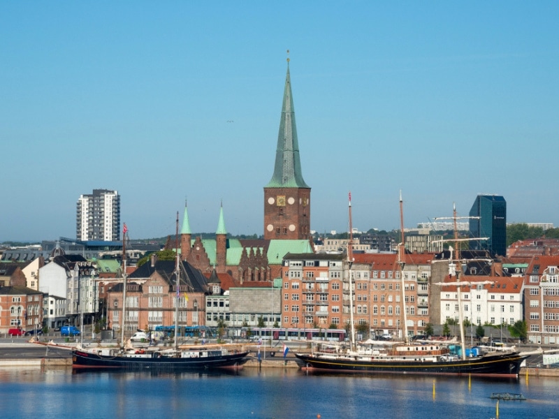 Sailboats buildings and towers of St. Clements Cathedral on the waterfront of Aarhus harbor