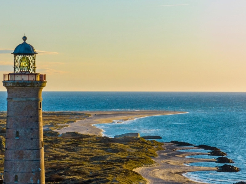 beach coastling with a tall grey concrete lighthouse cominating the skyline
