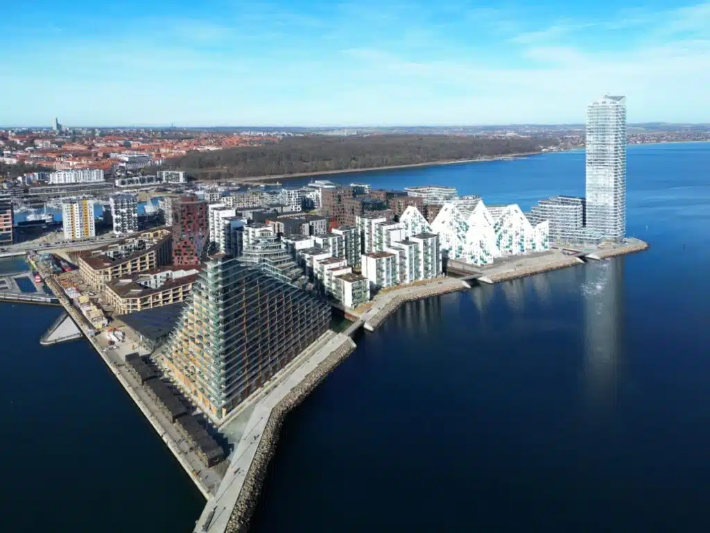 modern buildings on a peninsula with trees and a city in the background