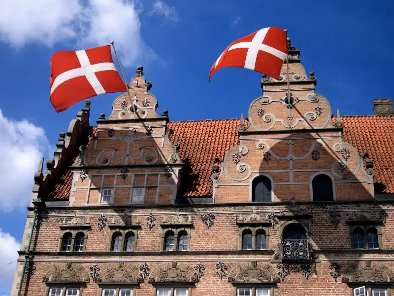 ornate red brick house with terracotta roof tiles and red flags with a white cross