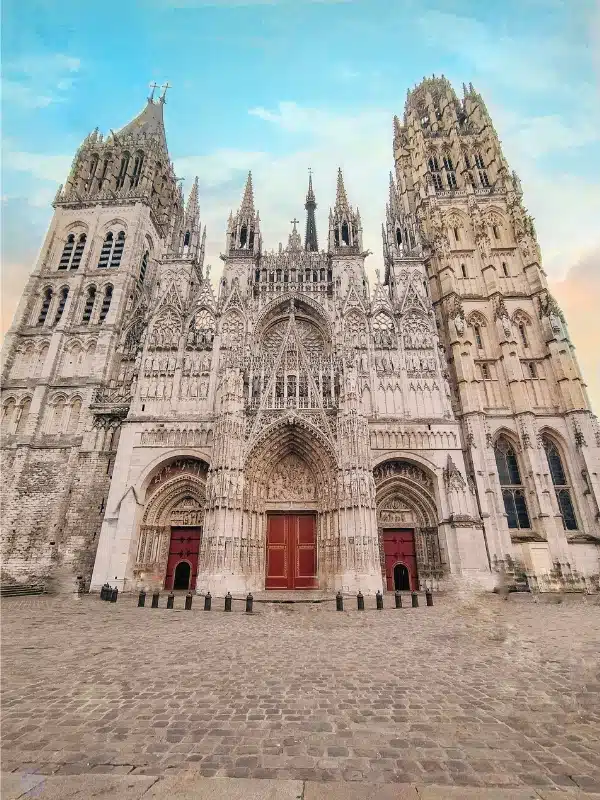 Large cathedral in a cobbled square with three red doors and large ornate towers