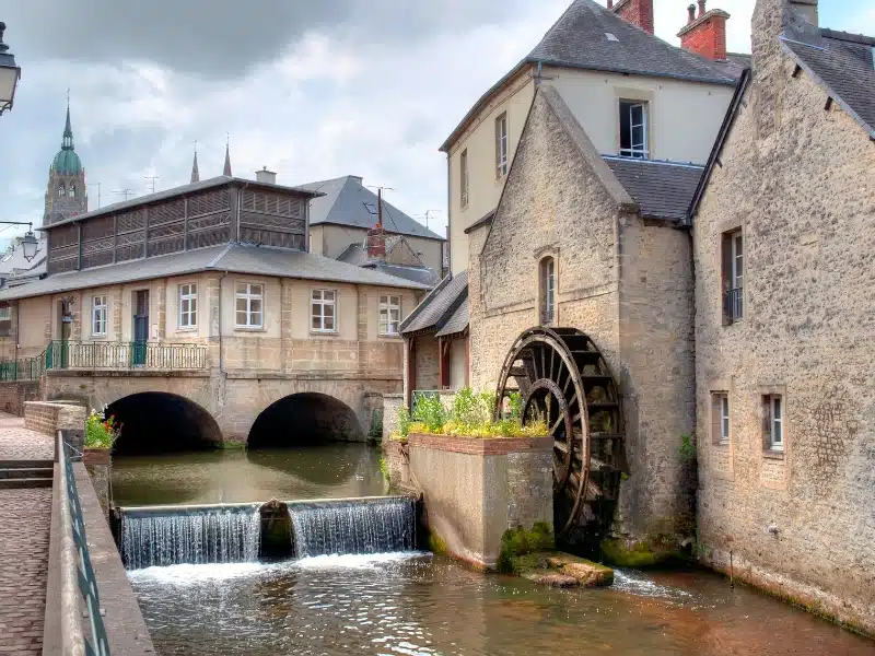 Old buildings and a weir next to a wooden water wheel