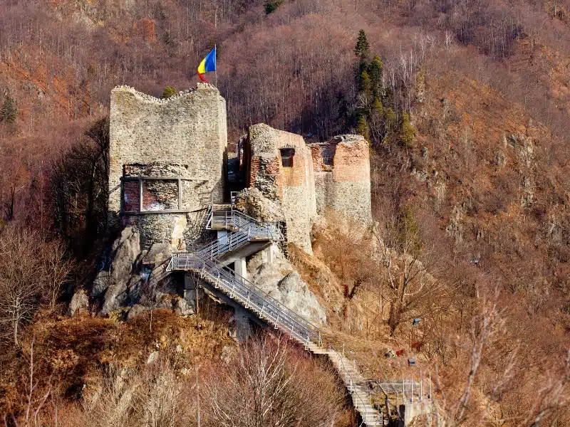 ancient castle ruins with red, yellow and blue Romanian flag flying
