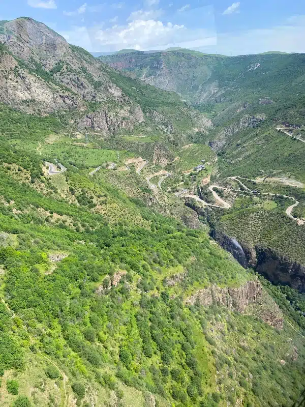 Switchback mountain road pictured from high up and surrouned by green mountains