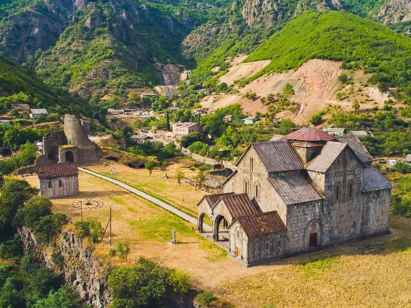 stone monastery and ramparts surrouned by parches grass and hills