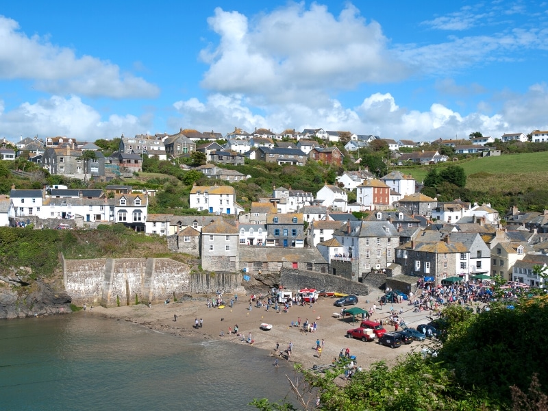 small harbout with cars and people, backed by stone and white houses