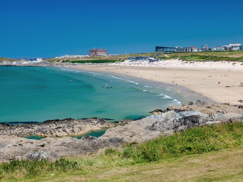 Long expanse of beach with sandy cliffs, buildings and turquoise sea