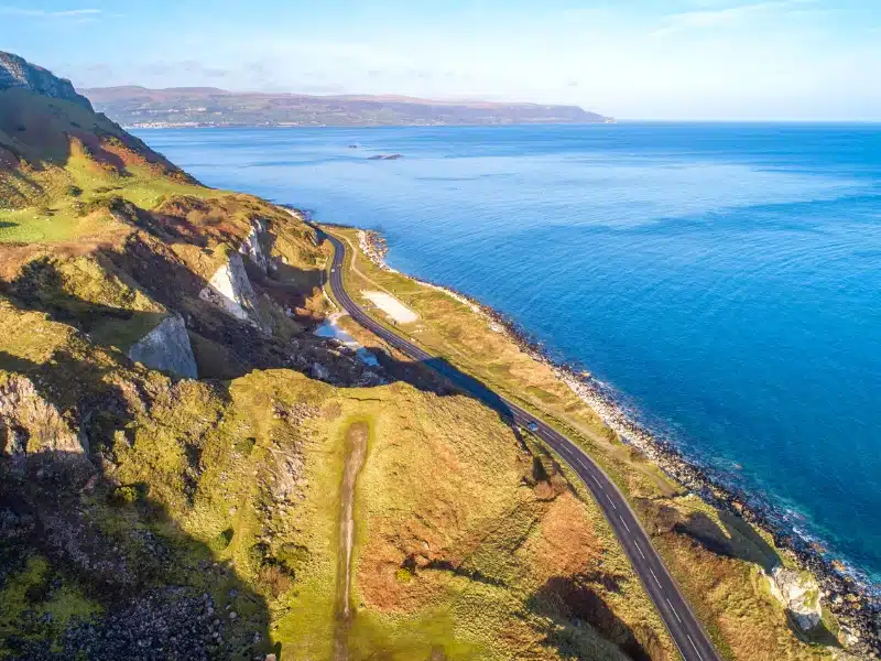 twisting road sandwiched between blue sea and mountains