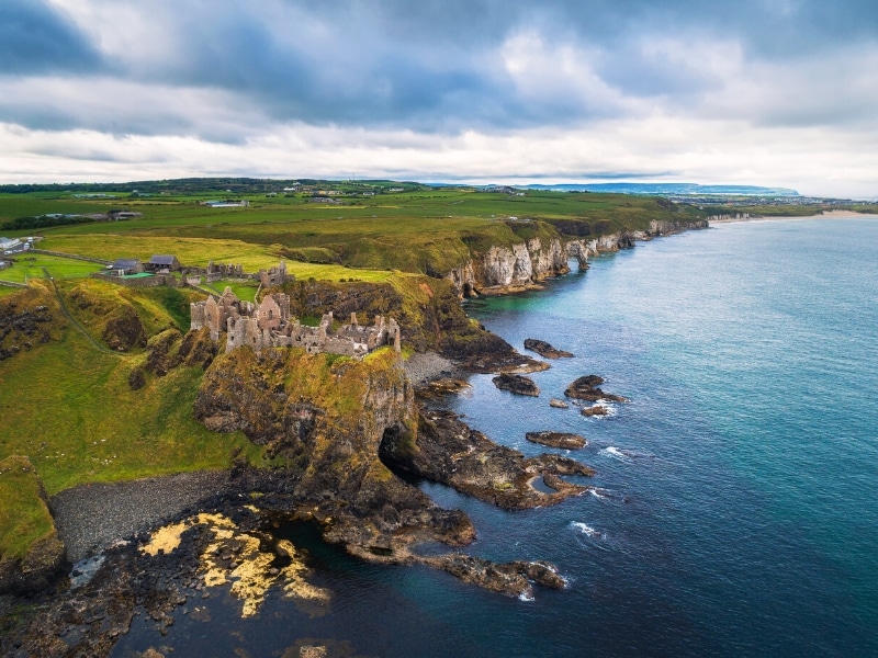 ancient building ruins atop a rocky cliff and blue sea