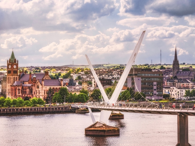 View of a modern bridge over a river and historic buildings in a city backdrop