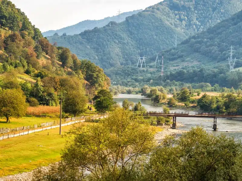 Romanian national park with a river and bridge surrounded by trees